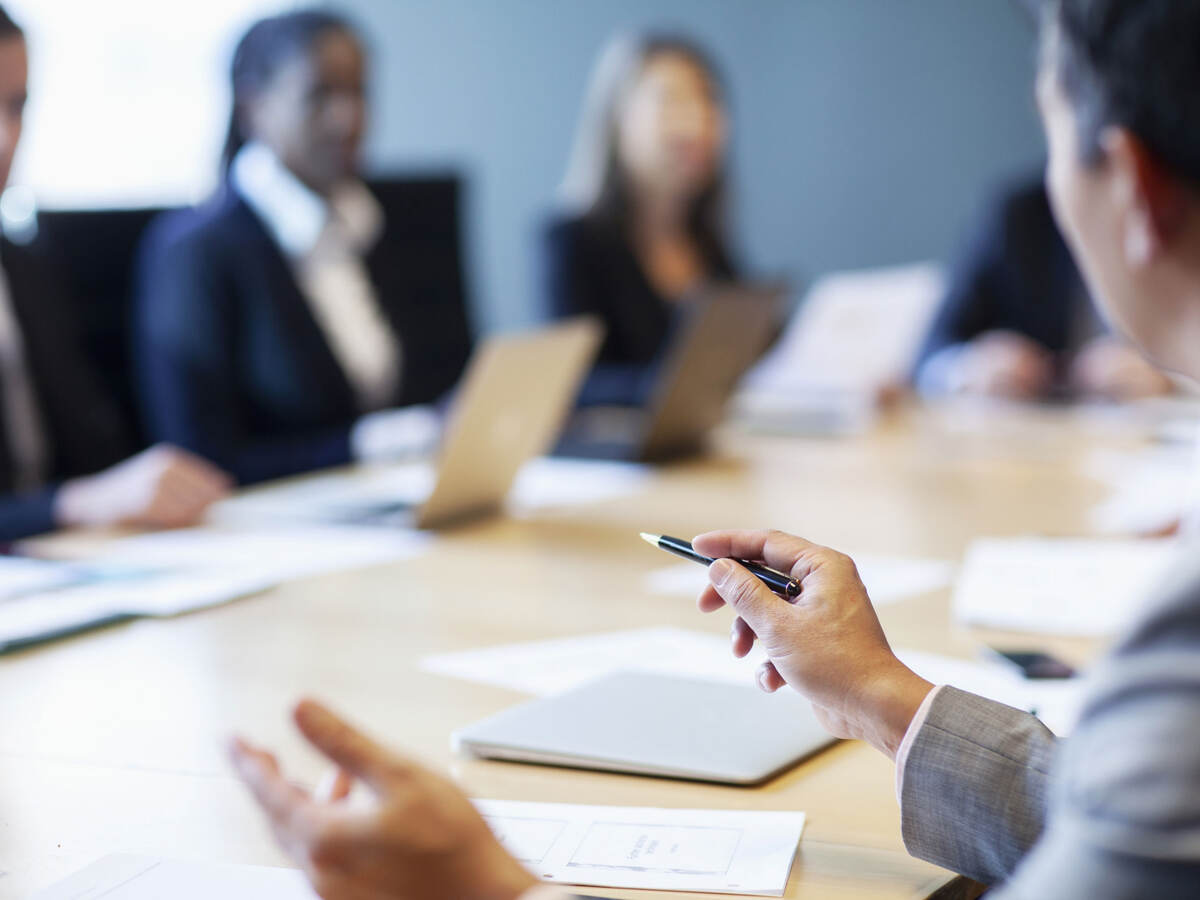 Closeup of a person gesturing ideas to work colleagues during a business meeting at board room conference table