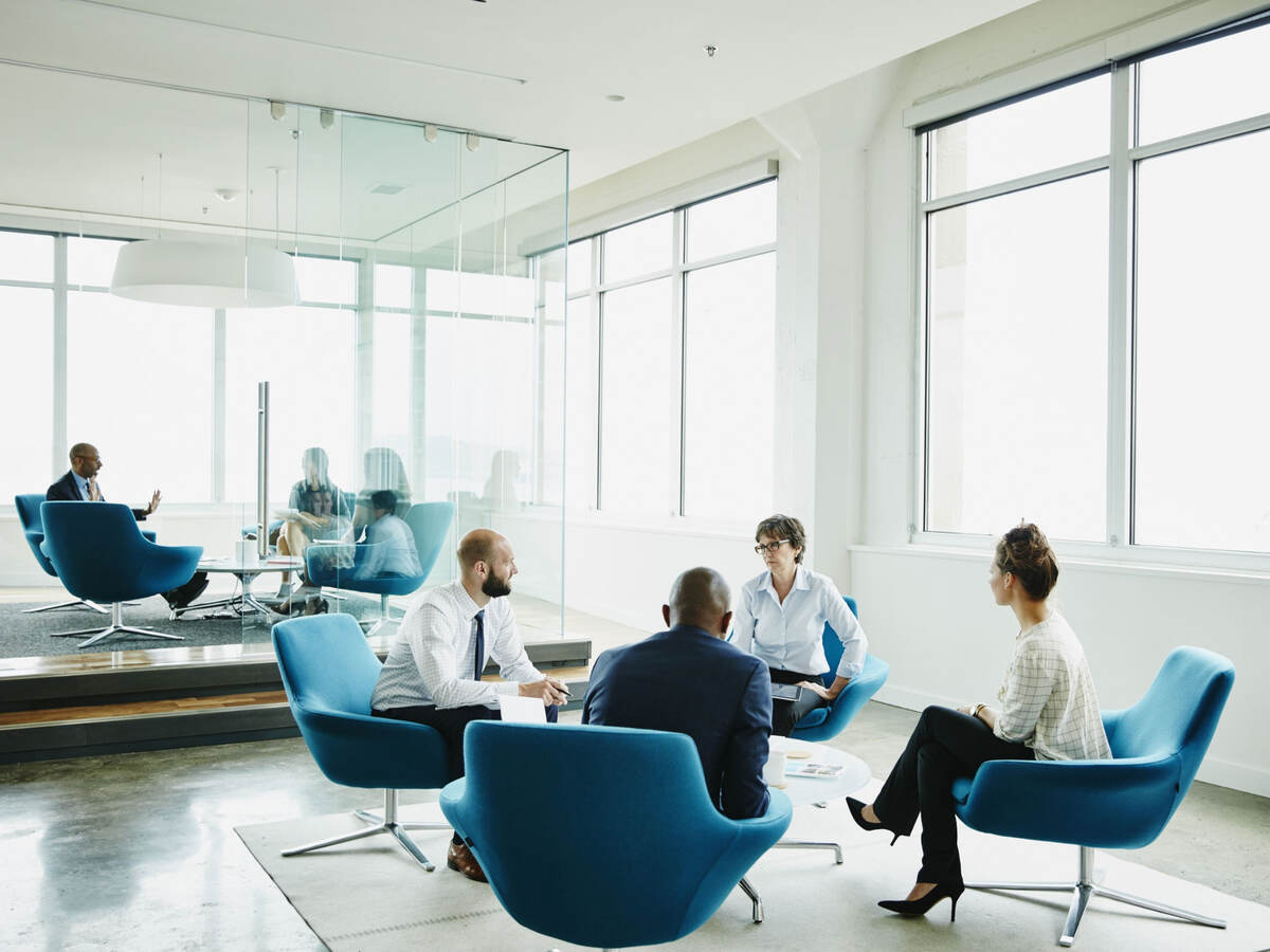 Group of business professionals having a meeting while sitting in blue chairs