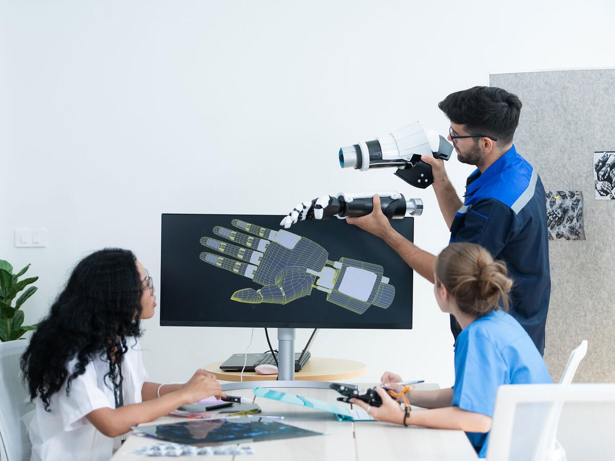 Technician reviewing a robotic hand with medical professionals