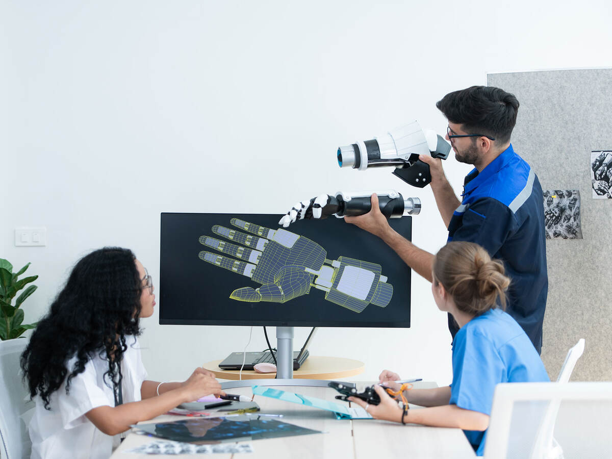 Technician reviewing a robotic hand with medical professionals