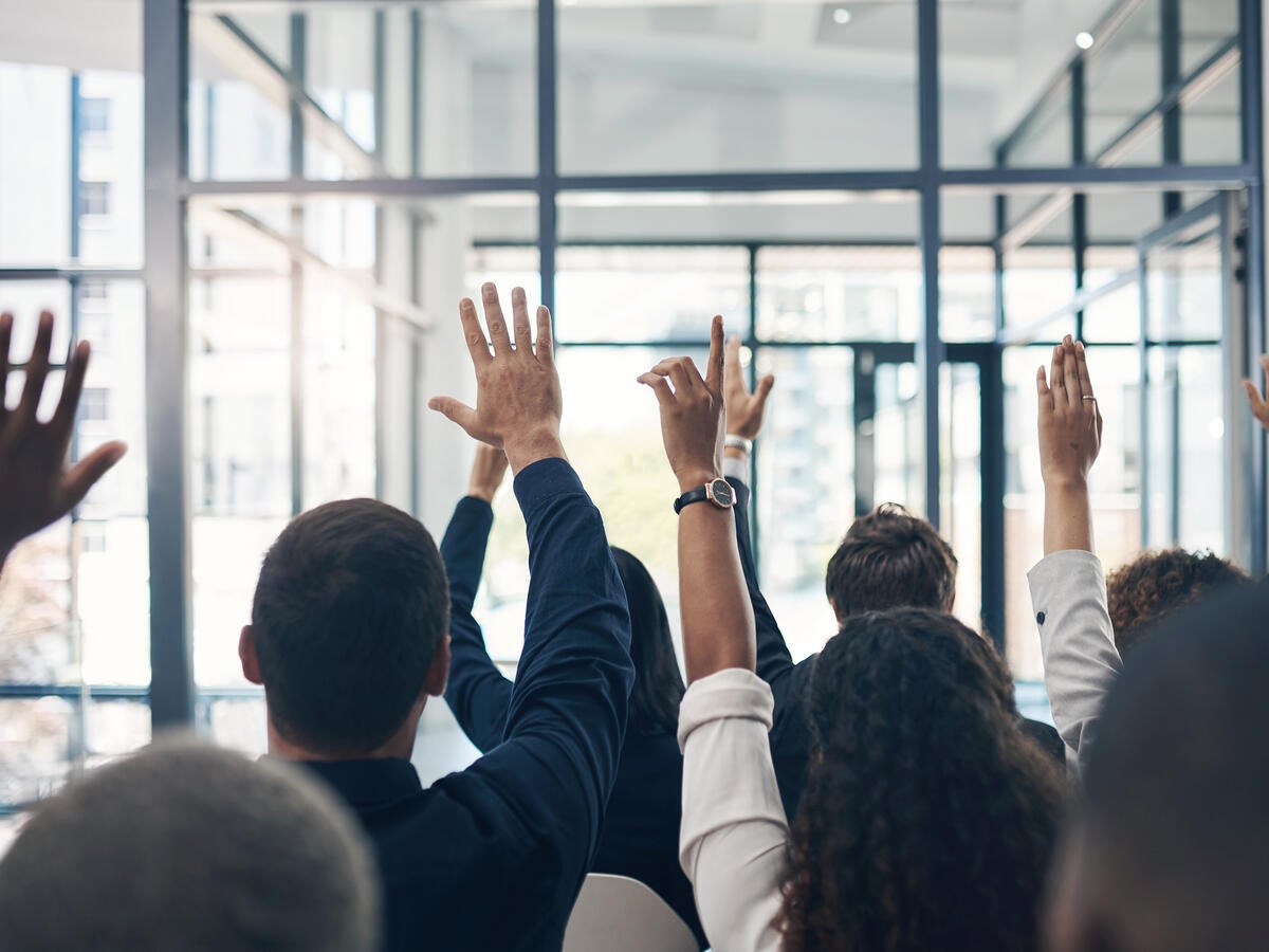 Group of people raising their hands to ask questions