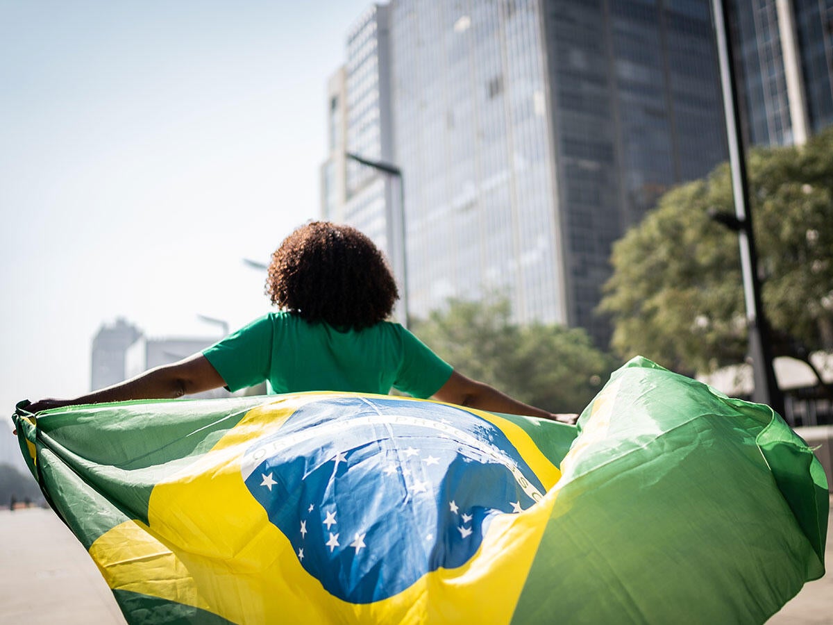 Person running through a city while holding the flag of Brazil