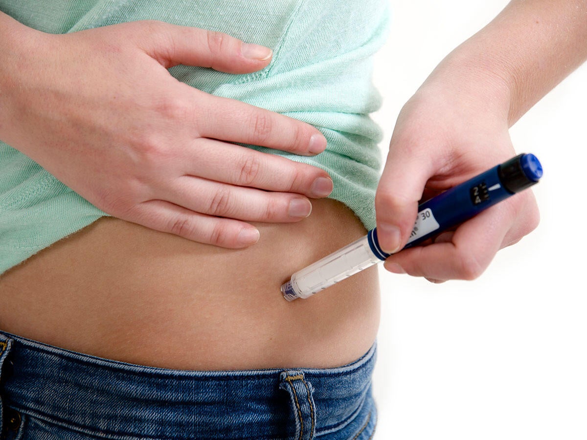 Person using an auto injector on their hip