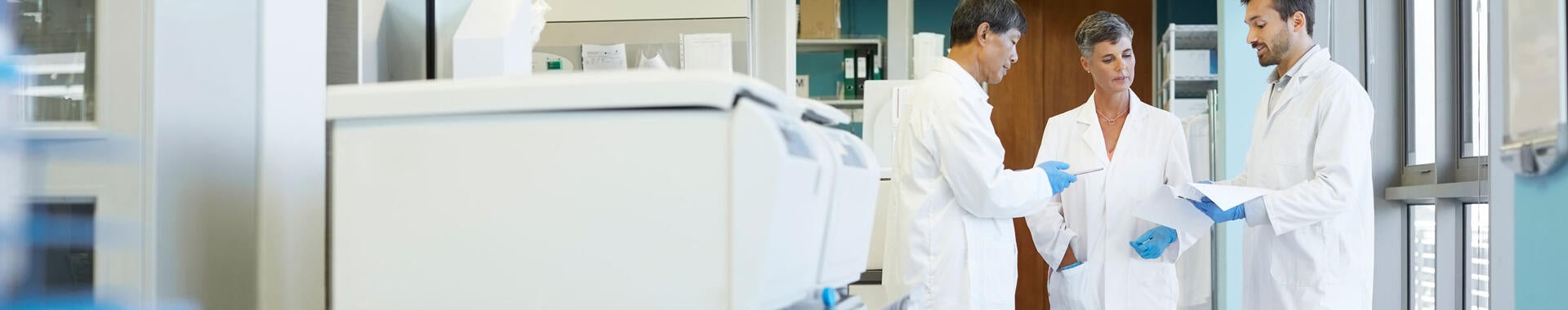 Group of lab technicians standing together looking at documents