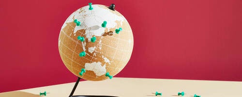 World map on globe with push pins for locations