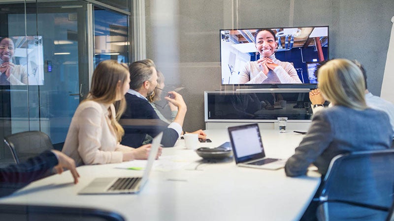 Meeting in a conference room with one virtual attendee on a monitor