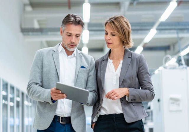 Two people standing in a lab looking at a tablet