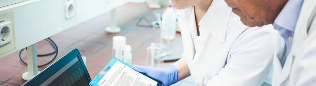 Two lab technicians looking at data on a computer