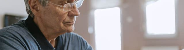 Senior man using blood pressure cuff in his home
