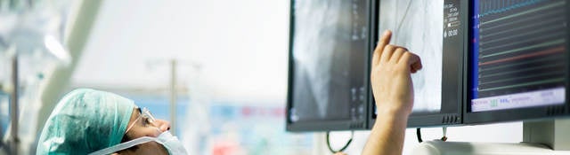 A surgeon is reviewing images on a computer screen