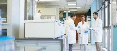 Group of lab technicians standing together looking at documents