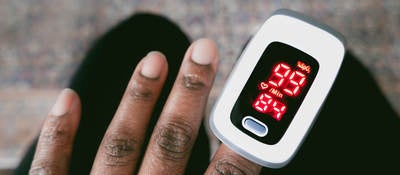 Close-up of unrecognizable black woman using a pulse oximeter to check her blood oxygen saturation level and heart rate