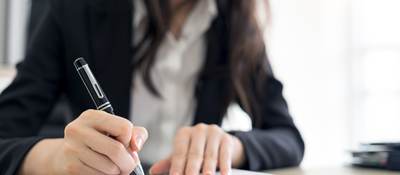 Person signing paperwork in an office 