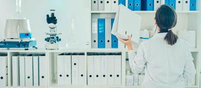 Lab tech putting away a binder on a shelf