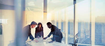 Business colleagues leaning over a table in an office while they work on their business strategy