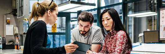 Three people discussing over a tablet