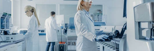 Team of Research Scientists Working On Computer, with Medical Equipment, Analyzing Blood and Genetic Material Samples with Special Machines in the Modern Laboratory.