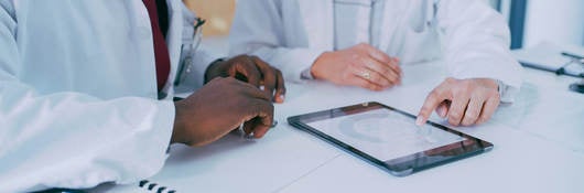 Shot of two doctors using a digital tablet during a discussion in a clinic