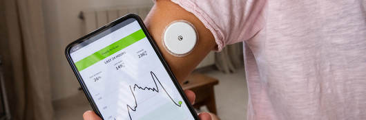 Phone with app being used for blood glucose monitoring.