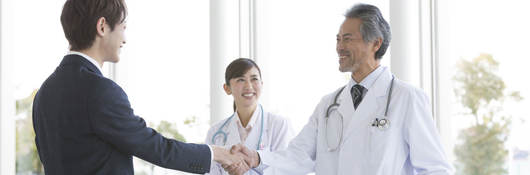 Person in a suit greeting two doctors