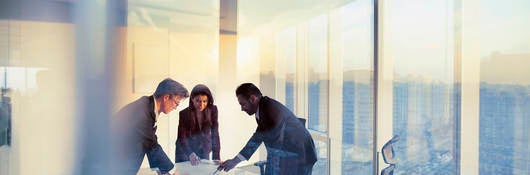 Business colleagues leaning over a table in an office while they work on their business strategy