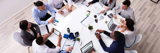 Overhead view of 12 people having a meeting at a square table
