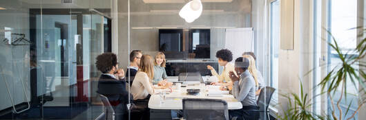 A board meeting inside a glass conference room