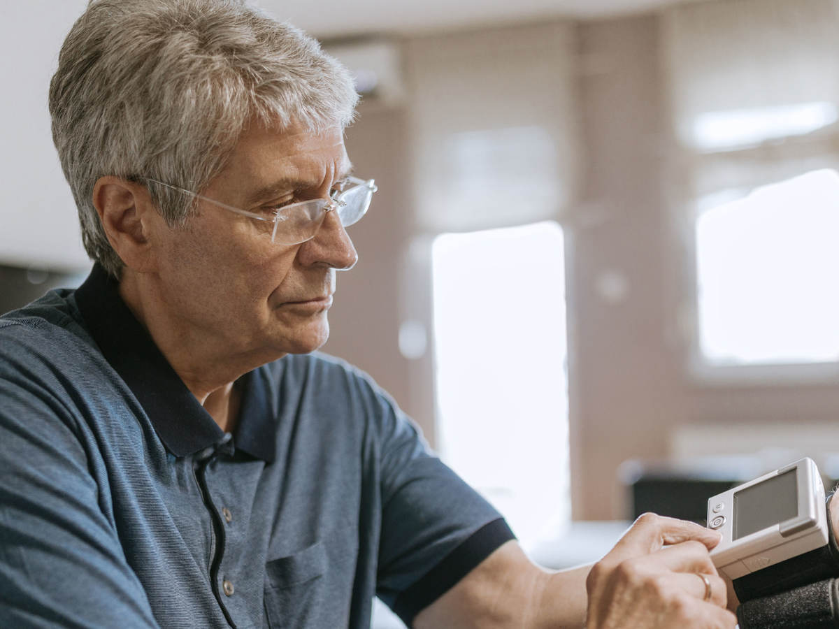 Senior man using blood pressure cuff in his home