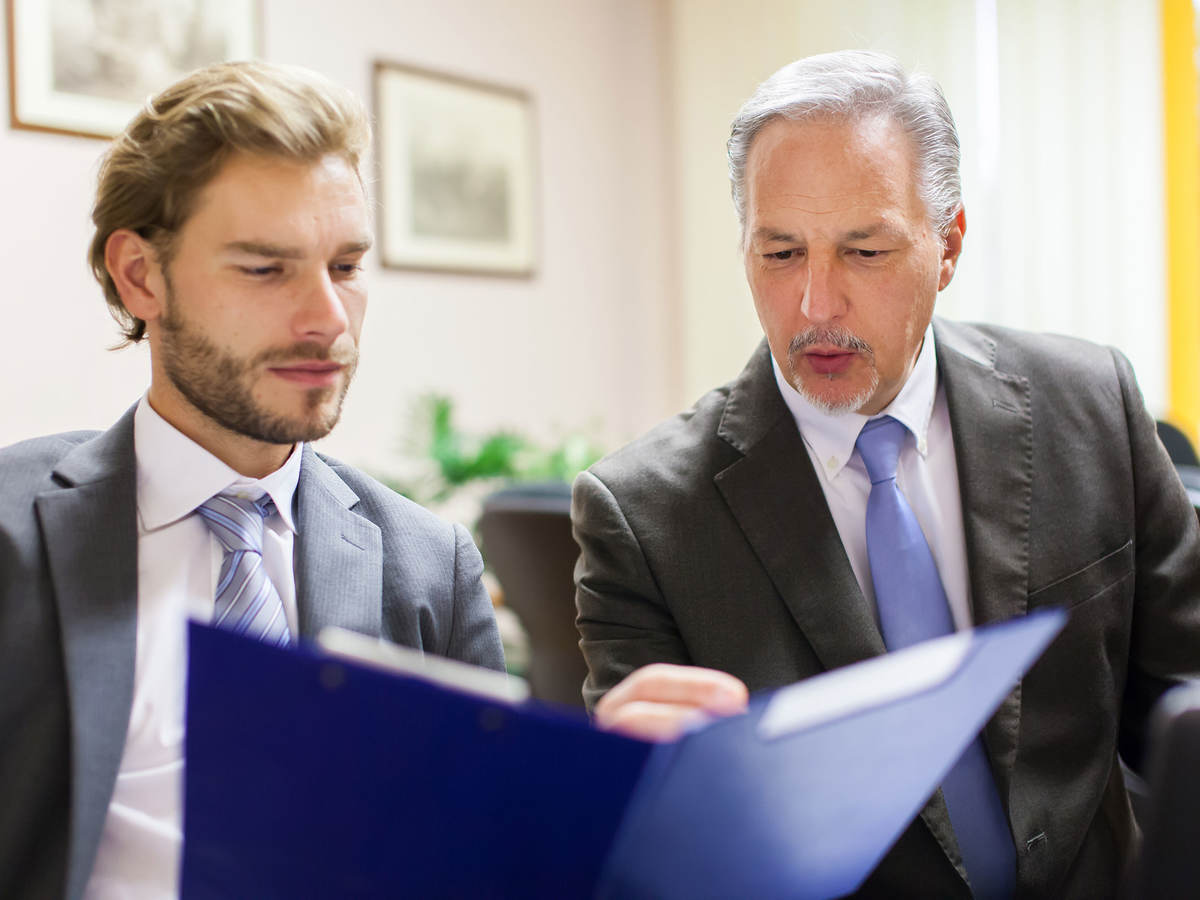 Two men in suits looking over a document