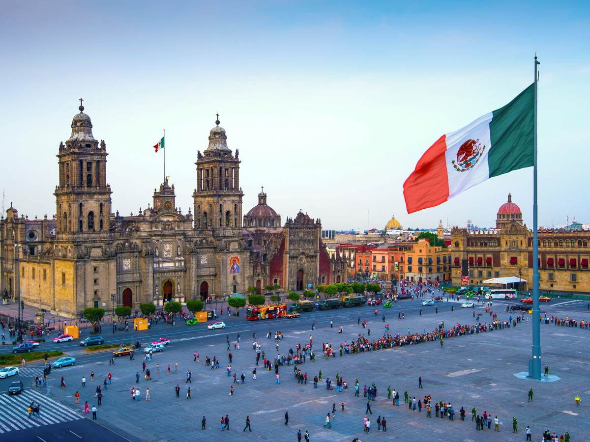 The Mexican flag flies over the Zocalo, the main square in Mexico City. The Metropolitan Cathedral faces the square, also referred to as Constitution Square.