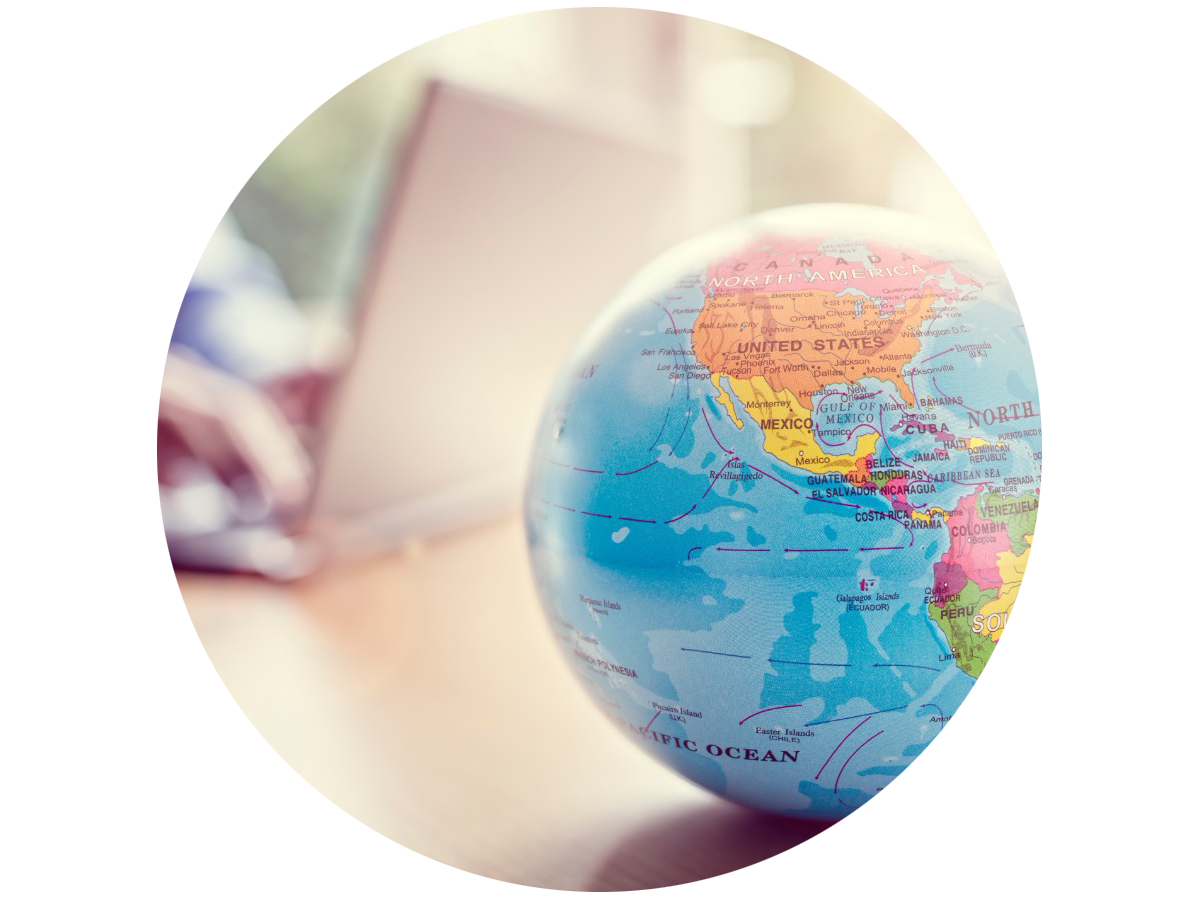 Globe sitting on a desk while someone uses a laptop in the background
