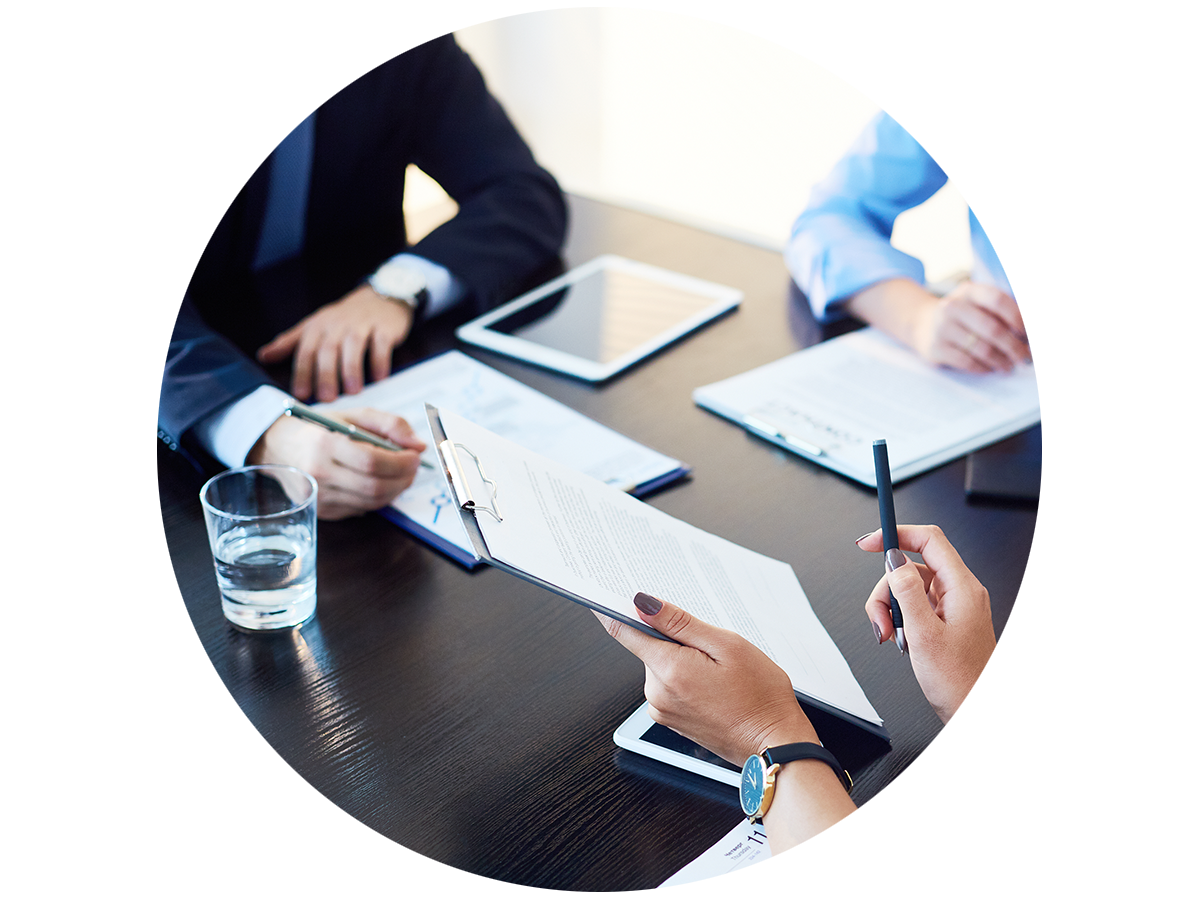 Three people discussing documents during a meeting in a conference room