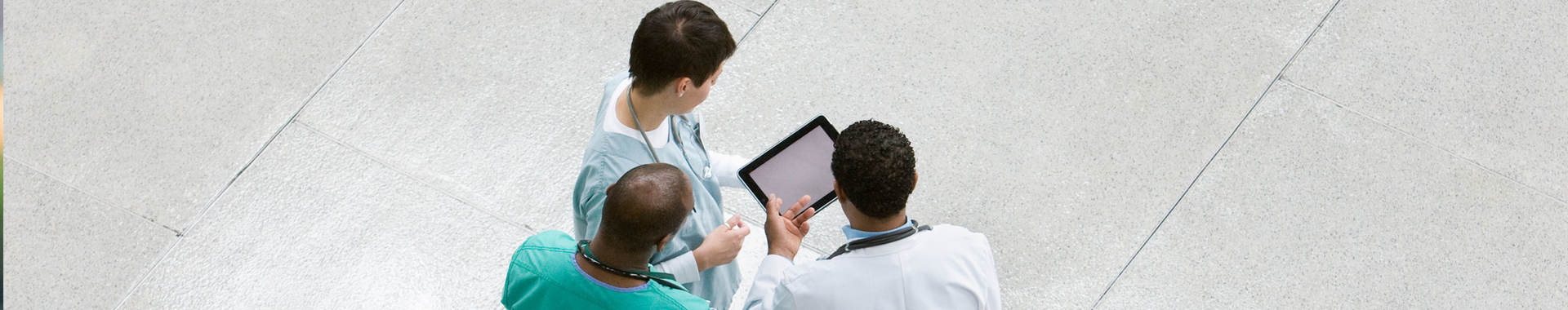 Overhead view of three doctors collaborating over a tablet 